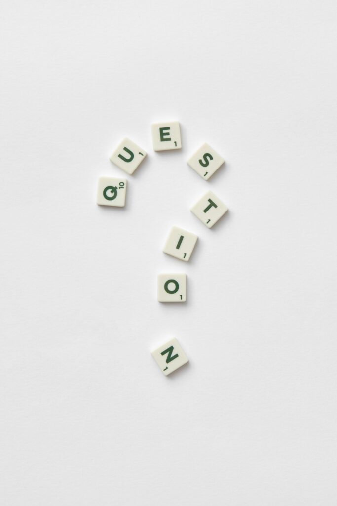 Artistic arrangement of letter tiles forming a question mark on a white background.